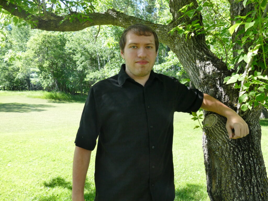 a man leans against a tree in a small field